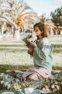 女子草坪野餐时亲吻手中的鲜花花束
