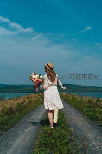 女子持花奔跑湖畔小径，蓝天白云下自由欢愉