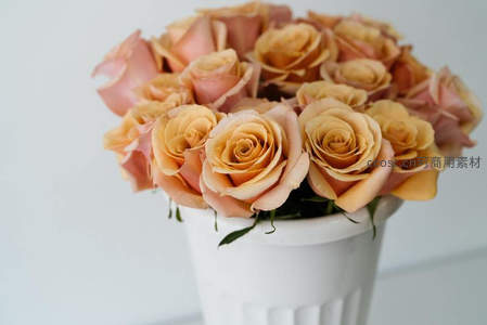 暖色玫瑰花束静置于白色花瓶中