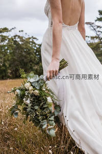 田野中白裙新娘背影持花束