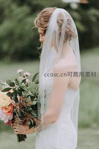 头戴薄纱的新娘静立田野捧花
