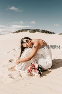 沙滩新娘低头沉思，花束相伴