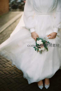 街角新娘轻抚裙摆，手握绿白小花束