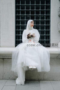 穆斯林新娘静坐窗前，洁白婚纱与头巾相映成辉