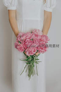 白衣女子手捧粉色牡丹花束