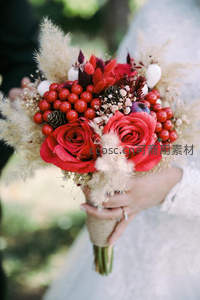 新娘手捧红玫瑰与浆果的婚礼花束