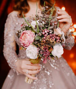 闪亮礼服中的新娘手捧粉白花束