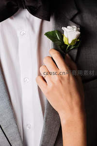 新郎西装翻领上白色玫瑰与婚戒特写