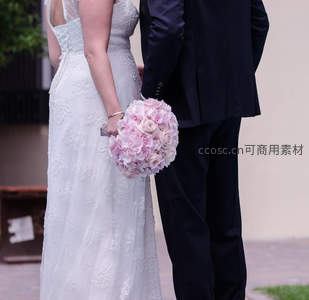 新人并肩而立，新娘手握粉玫瑰花束