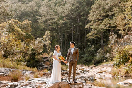 溪边岩石上新人对视牵手的自然写真