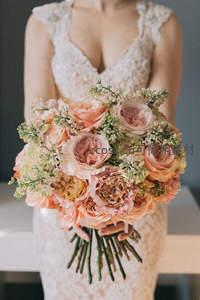 新娘手持粉色玫瑰花束，优雅蕾丝裙摆