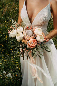 田野中新娘持花，野花点缀浪漫婚纱