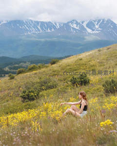 女子静坐花丛远眺雪山美景