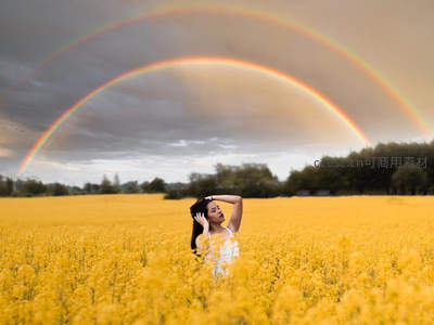 彩虹之下油菜田，女子沉醉自然美