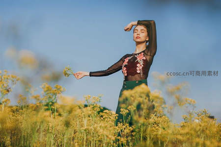 女子立于花海，优雅姿态融入自然