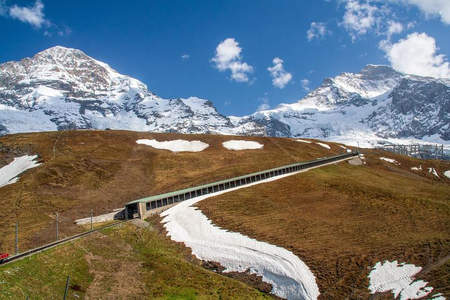 阿尔卑斯山麓，蜿蜒铁路穿越雪野草坡
