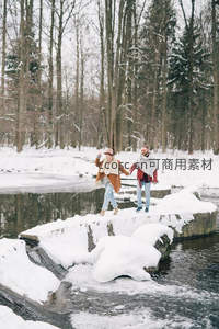 情侣手牵手踏雪过溪石桥