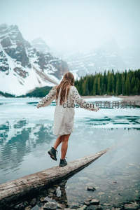 女子湖边木桩上平衡跳跃赏雪山