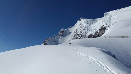 登山者踏雪攀登巍峨雪山之巅