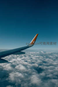 飞机舷窗外的云海，蓝天与橙翼相映成趣