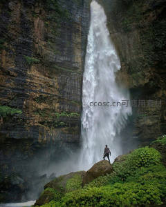 悬崖峭壁间飞瀑直下，旅人驻足仰望