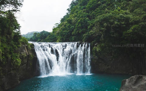 层叠瀑布注入碧潭，四周绿树环抱如画