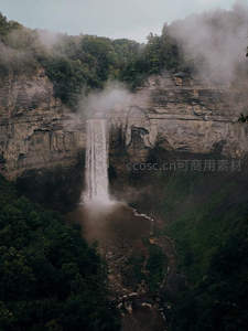 云雾缭绕山谷中，瀑布自崖顶倾泻而下