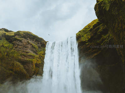 仰视视角下瀑布从青苔岩壁倾泻