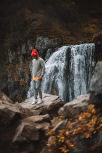 红帽少年立于瀑布前