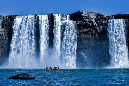 瀑布前小舟载客，水雾弥漫如仙境