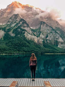 少女伫立湖边，远眺雪山云海