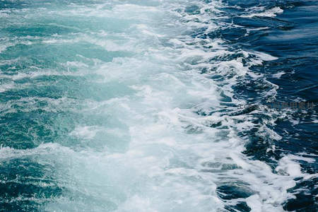 船尾激起的白色浪花在碧蓝海面延展