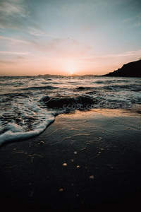 夕阳西下海浪轻抚黑沙滩