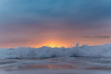 夕阳海浪翻涌，天空染上橙粉霞光
