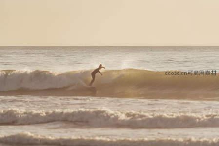 冲浪者剪影驰骋金色海浪之上