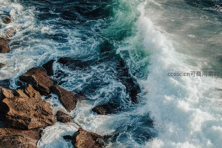巨浪撞击礁石，激起白色浪花如雪