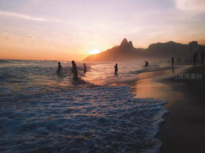 黄昏沙滩上的人群剪影与山峦