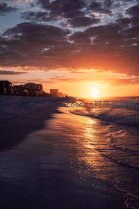 金色夕阳洒满海岸线，城市剪影与海浪共舞