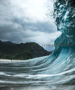巨浪卷起水花，远山云层密布的海岸奇观