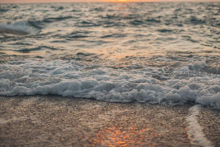 夕阳海浪轻抚沙滩泡沫