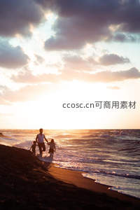 夕阳下海边散步的一家三口
