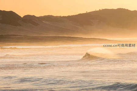 金色夕阳下的海岸线与翻滚海浪