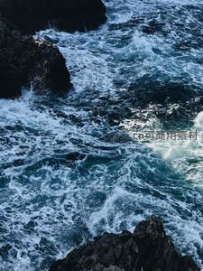 深蓝海浪撞击嶙峋黑岩的瞬间