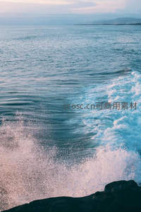 海浪拍岸激起绚烂水花与远方山峦