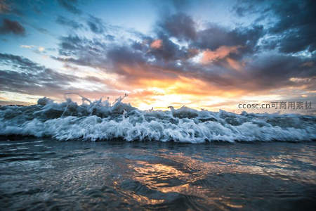 日落时分海浪拍岸金光洒满翻滚泡沫