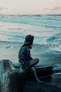 女子静坐海边木桩凝望远方