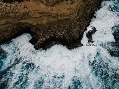 航拍视角下海浪冲击嶙峋海岸的壮丽景象