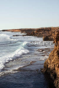 阳光洒落海岸线，波涛轻抚岩岸的宁静时刻