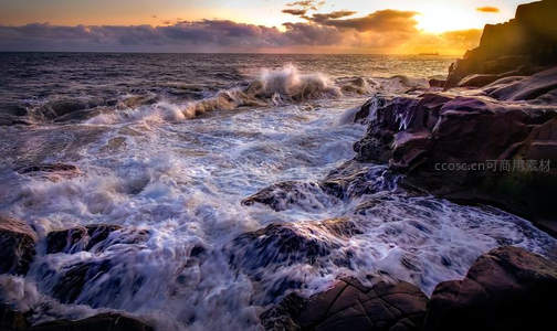 夕阳下海浪拍打岩石的壮丽景象