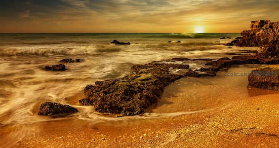 金色黄昏中柔美海浪轻抚礁石滩涂